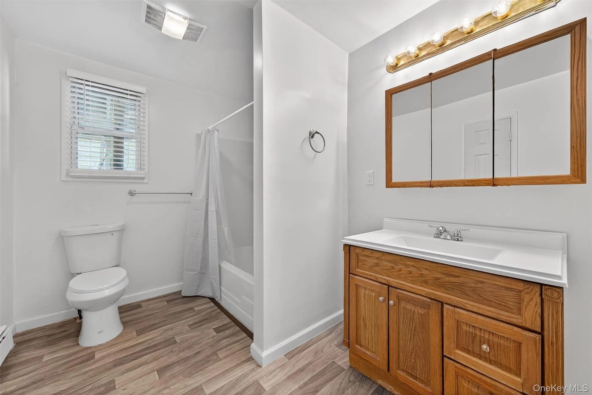 Bathroom with shower / bath combo with shower curtain, vanity, and light wood-style flooring Bathroom with shower / bath combo with shower curtain, vanity, and light wood-style flooring