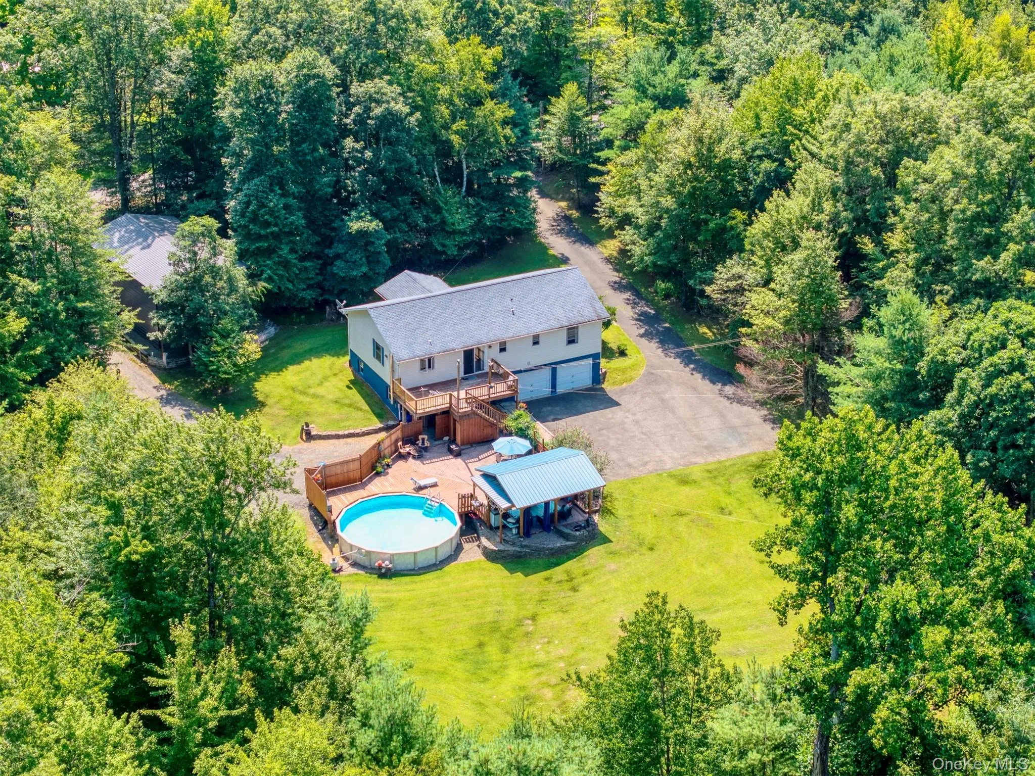 Aerial view of property and surrounding area featuring a forest and a pool area Aerial view of property and surrounding area featuring a forest and a pool area