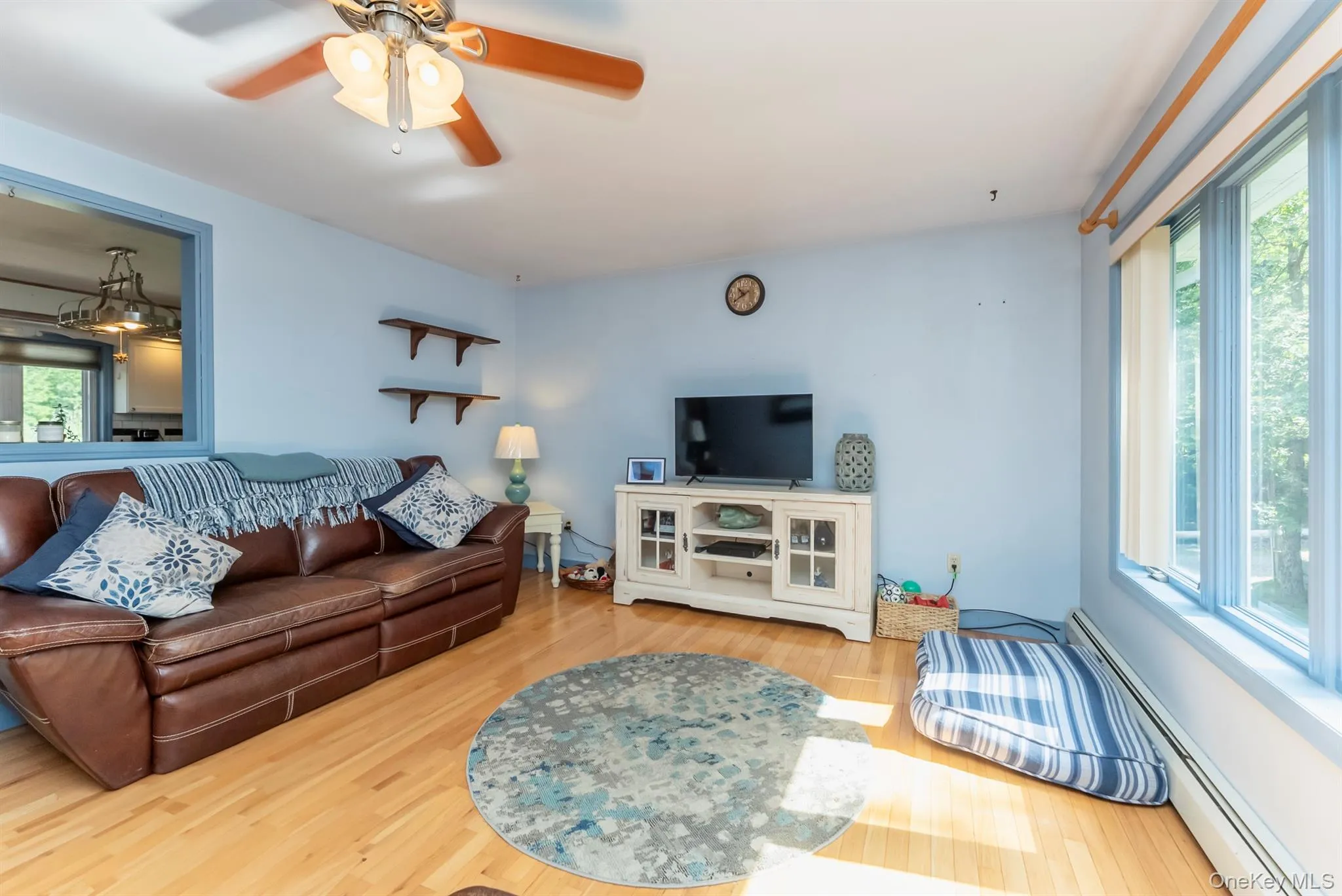 Living room featuring a baseboard heating unit, light wood-style flooring, and a ceiling fan Living room featuring a baseboard heating unit, light wood-style flooring, and a ceiling fan