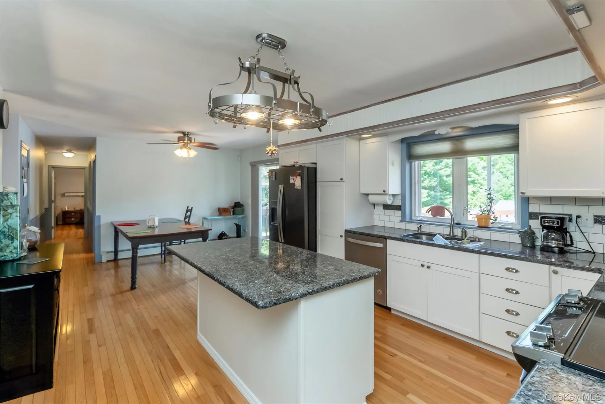 Kitchen with a kitchen island, white cabinets, appliances with stainless steel finishes, light wood-style flooring, and healthy amount of natural light Kitchen with a kitchen island, white cabinets, appliances with stainless steel finishes, light wood-style flooring, and healthy amount of natural light