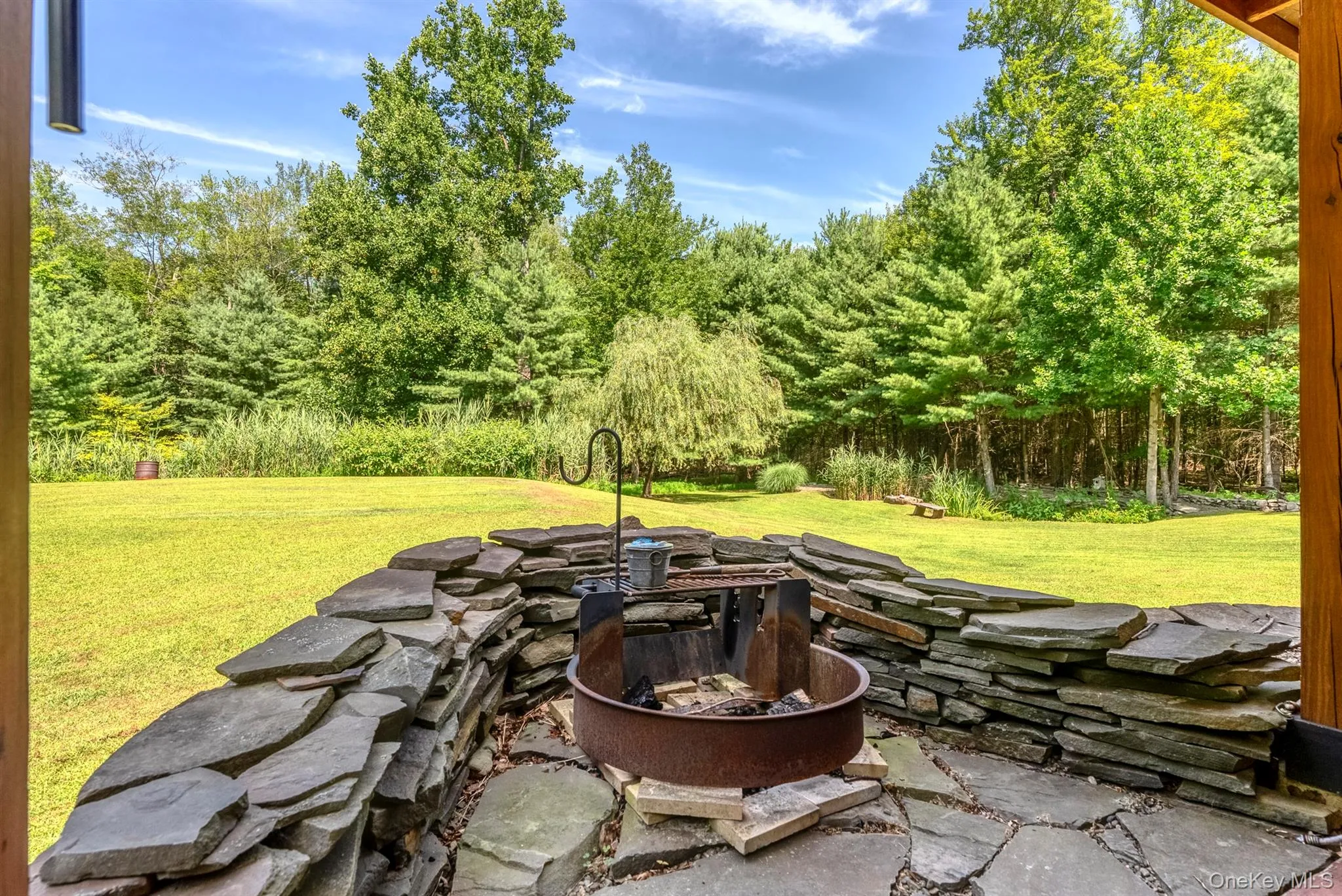 View of patio featuring a fire pit and view of scattered trees View of patio featuring a fire pit and view of scattered trees