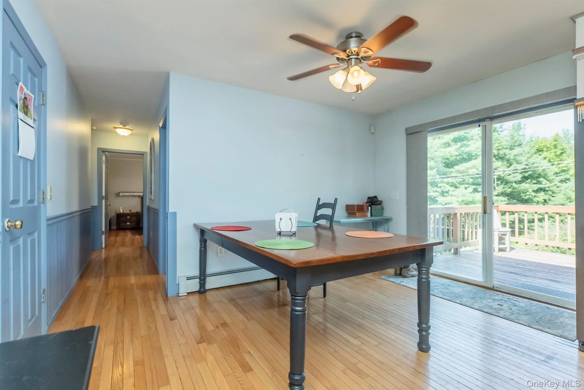 Dining space featuring light wood-style flooring, a baseboard radiator, ceiling fan, and wainscoting Dining space featuring light wood-style flooring, a baseboard radiator, ceiling fan, and wainscoting
