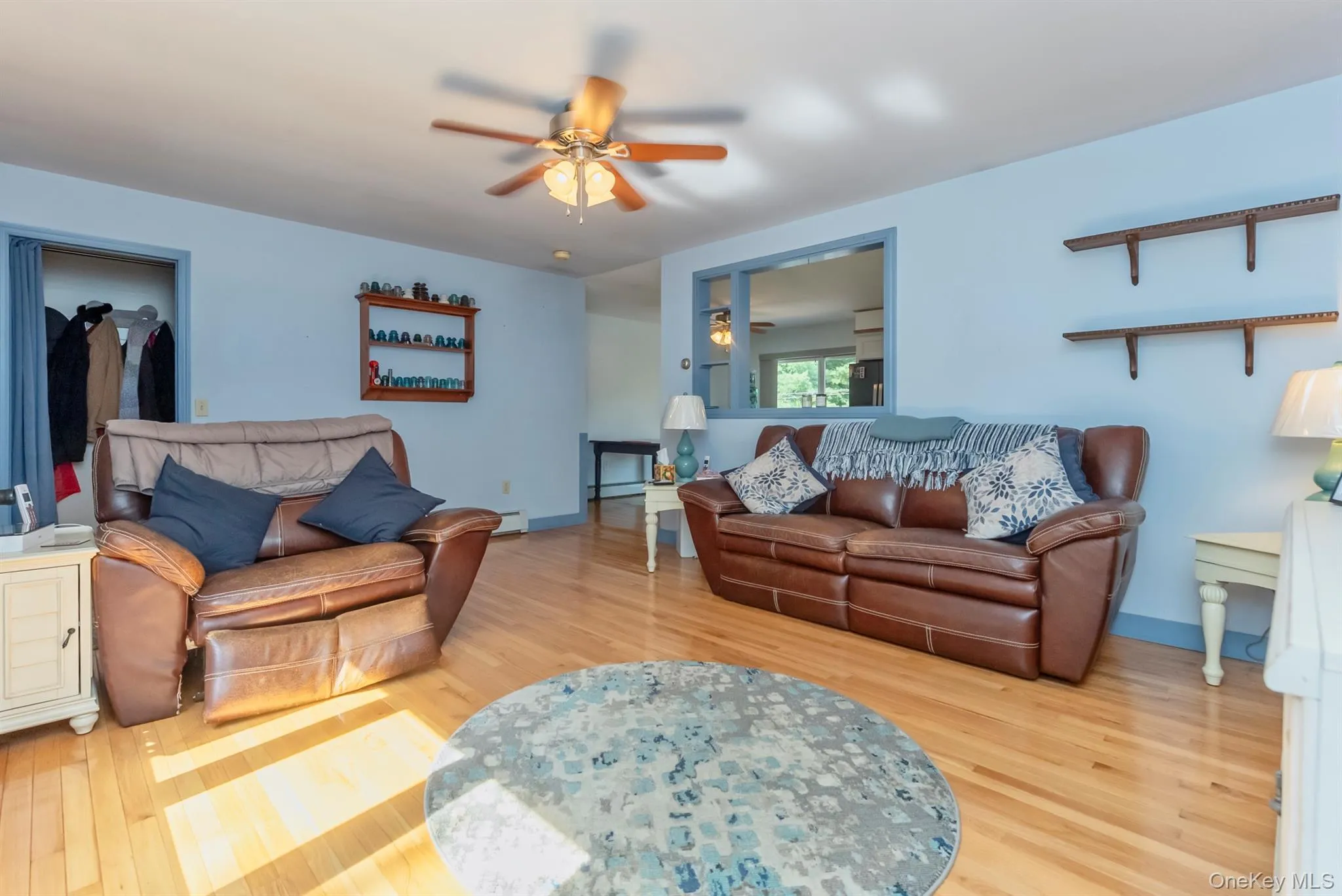 Living area featuring a ceiling fan, light wood-style flooring, and a baseboard heating unit Living area featuring a ceiling fan, light wood-style flooring, and a baseboard heating unit