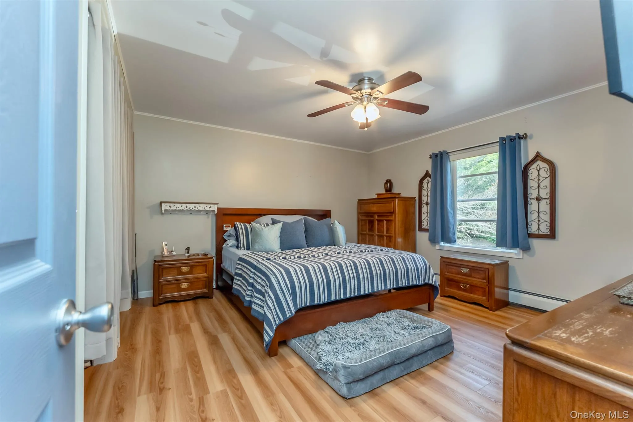 Bedroom featuring light wood-type flooring, ornamental molding, a baseboard radiator, and ceiling fan Bedroom featuring light wood-type flooring, ornamental molding, a baseboard radiator, and ceiling fan
