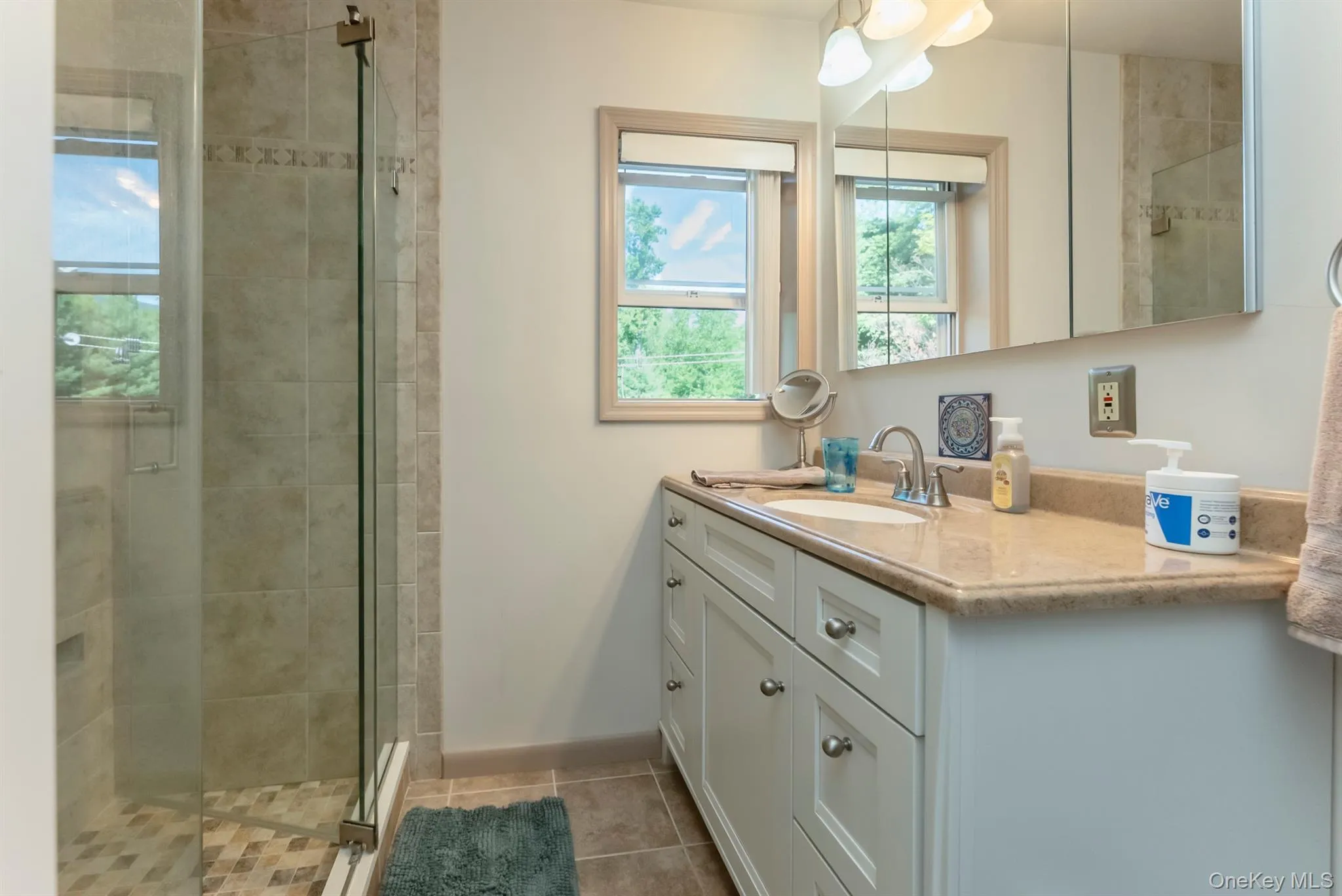 Full bath featuring vanity, a stall shower, and light tile patterned floors Full bath featuring vanity, a stall shower, and light tile patterned floors
