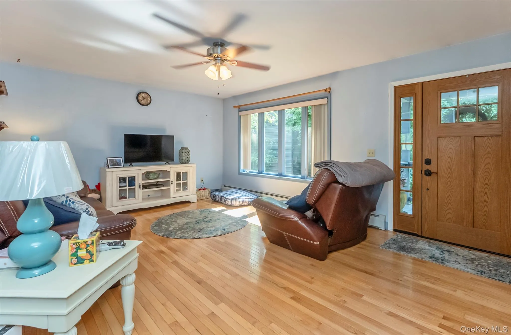 Living room featuring wood-type flooring, a baseboard radiator, and ceiling fan Living room featuring wood-type flooring, a baseboard radiator, and ceiling fan