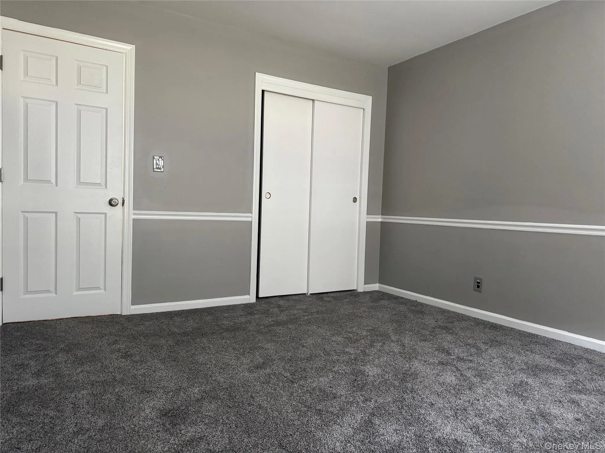 Unfurnished bedroom with dark carpet and a closet Unfurnished bedroom with dark carpet and a closet