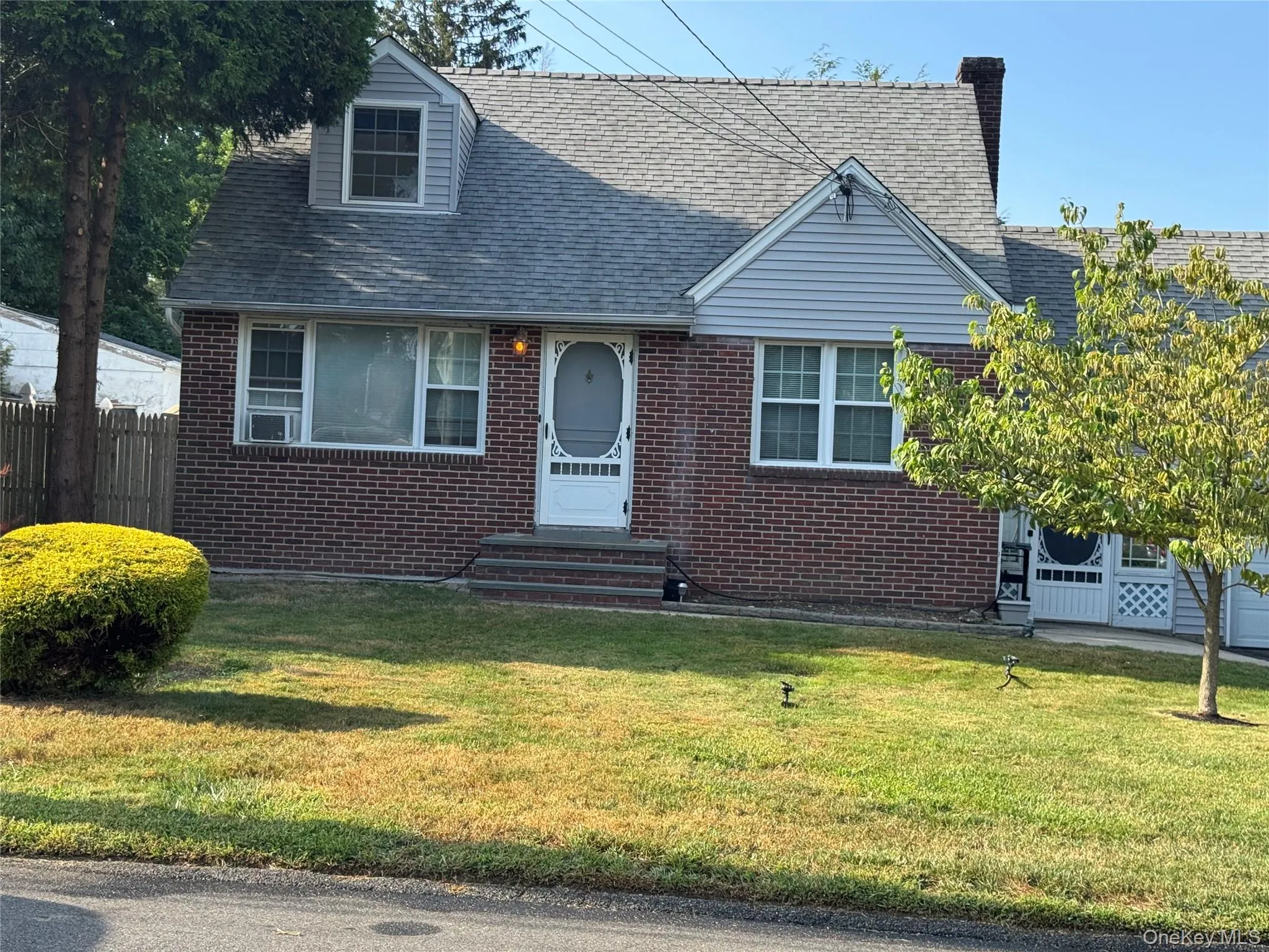 Cape cod house with brick siding and a shingled roof Cape cod house with brick siding and a shingled roof