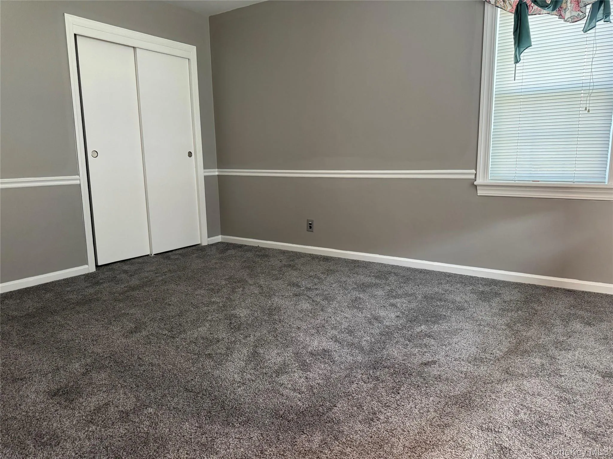 Unfurnished bedroom with dark colored carpet and a closet Unfurnished bedroom with dark colored carpet and a closet