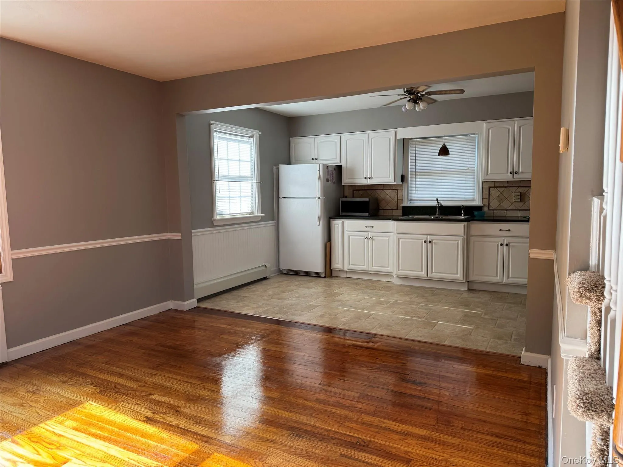 Kitchen with dark countertops, light wood-type flooring, white cabinets, and backsplash Kitchen with dark countertops, light wood-type flooring, white cabinets, and backsplash