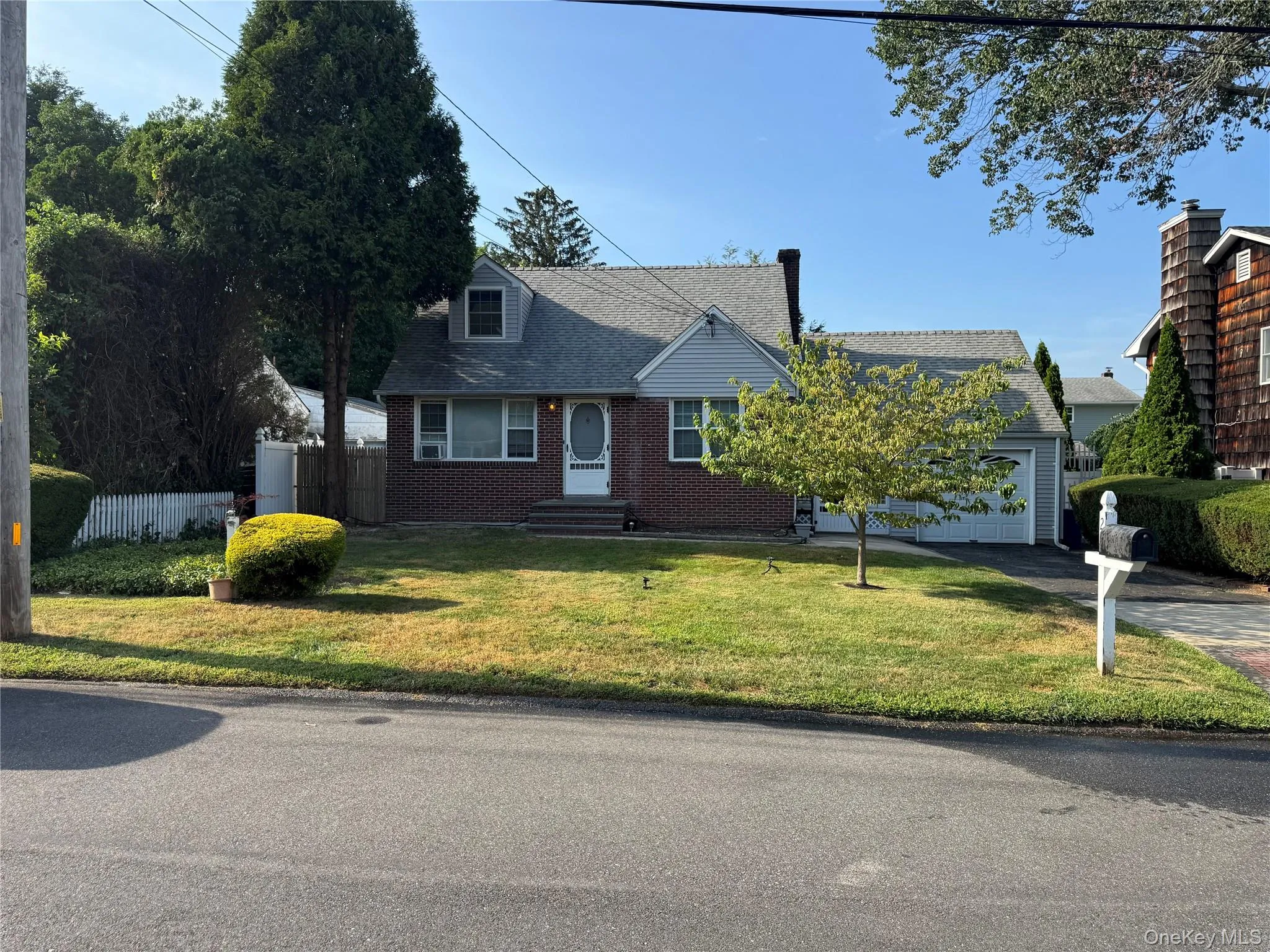 Cape cod-style house featuring driveway, brick siding, roof with shingles, and an attached garage Cape cod-style house featuring driveway, brick siding, roof with shingles, and an attached garage