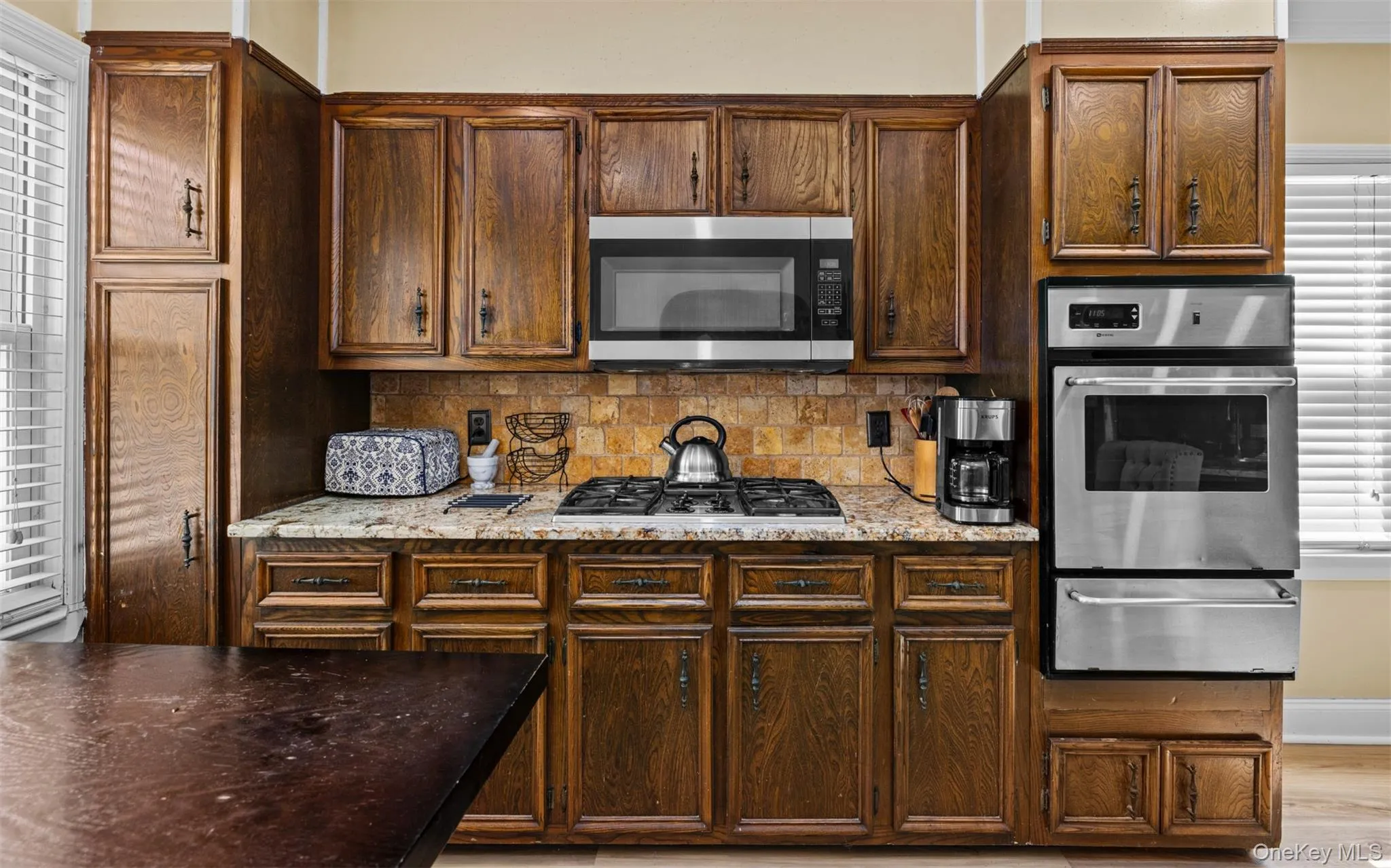 Kitchen with stainless steel appliances, backsplash, a warming drawer, light stone countertops, and light wood-type flooring Kitchen with stainless steel appliances, backsplash, a warming drawer, light stone countertops, and light wood-type flooring