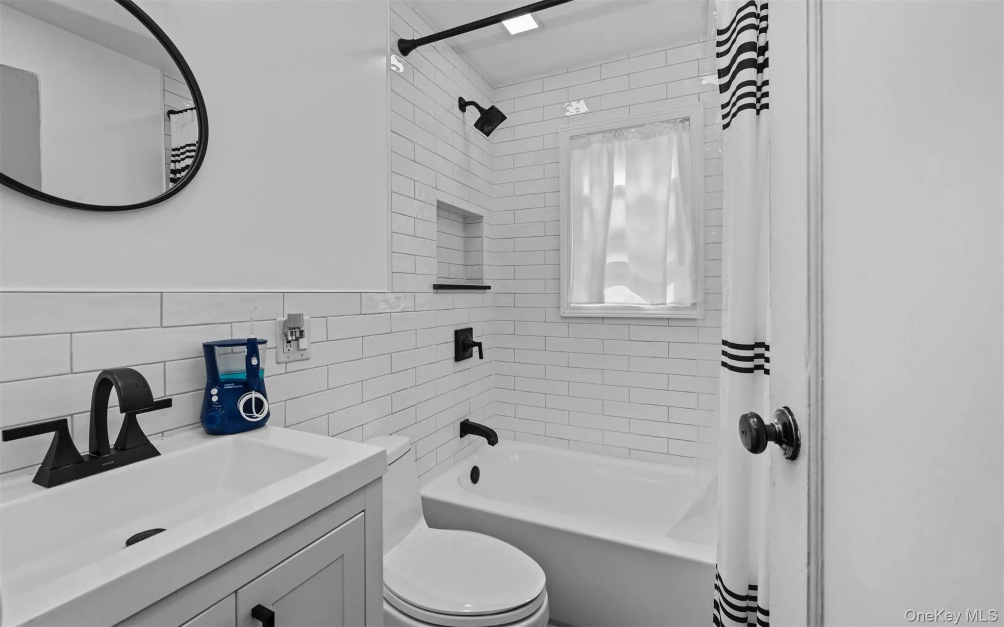 Bathroom featuring shower / bath combo, vanity, tile walls, and backsplash Bathroom featuring shower / bath combo, vanity, tile walls, and backsplash