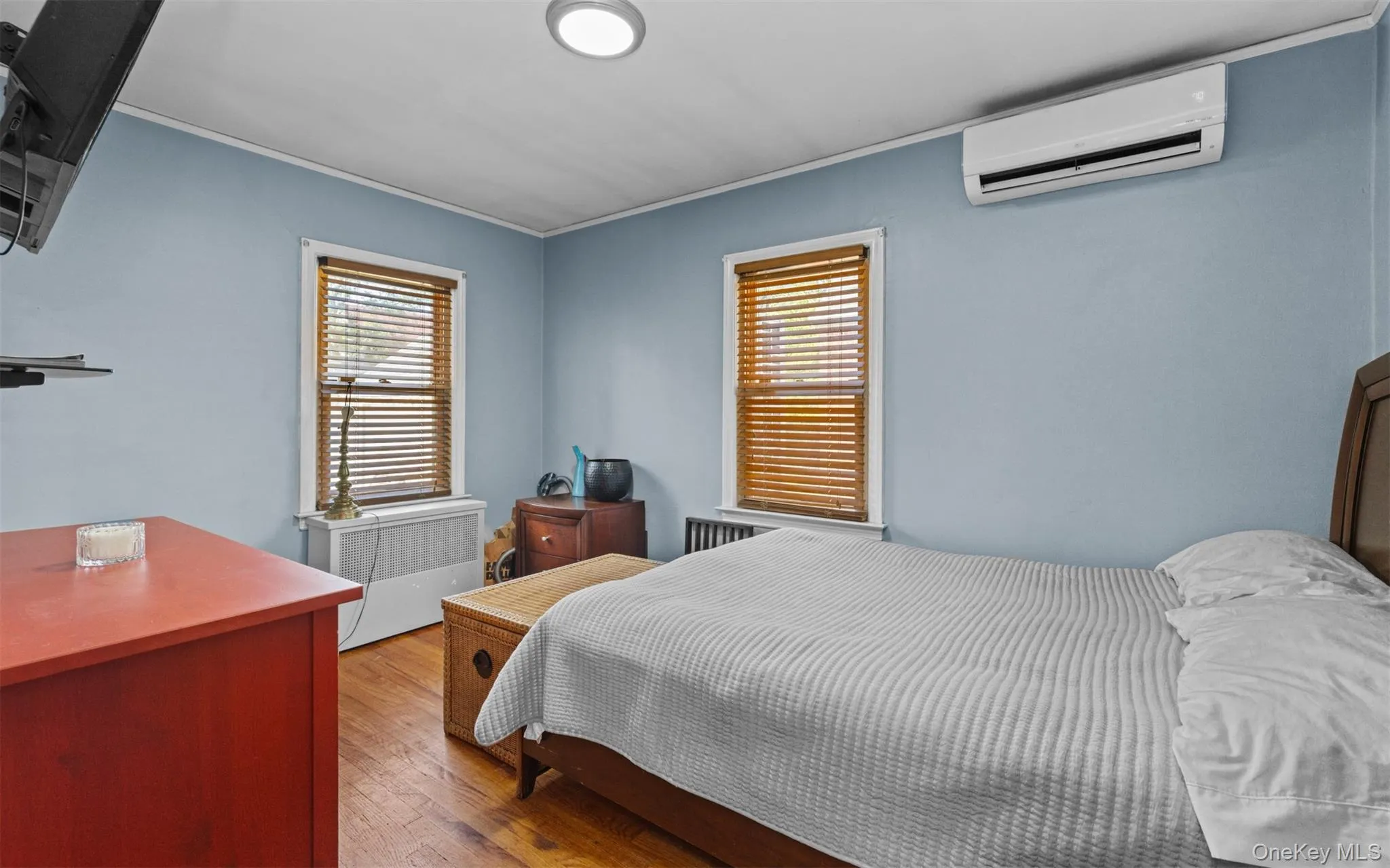 Bedroom with wood finished floors, a wall mounted AC, and crown molding Bedroom with wood finished floors, a wall mounted AC, and crown molding