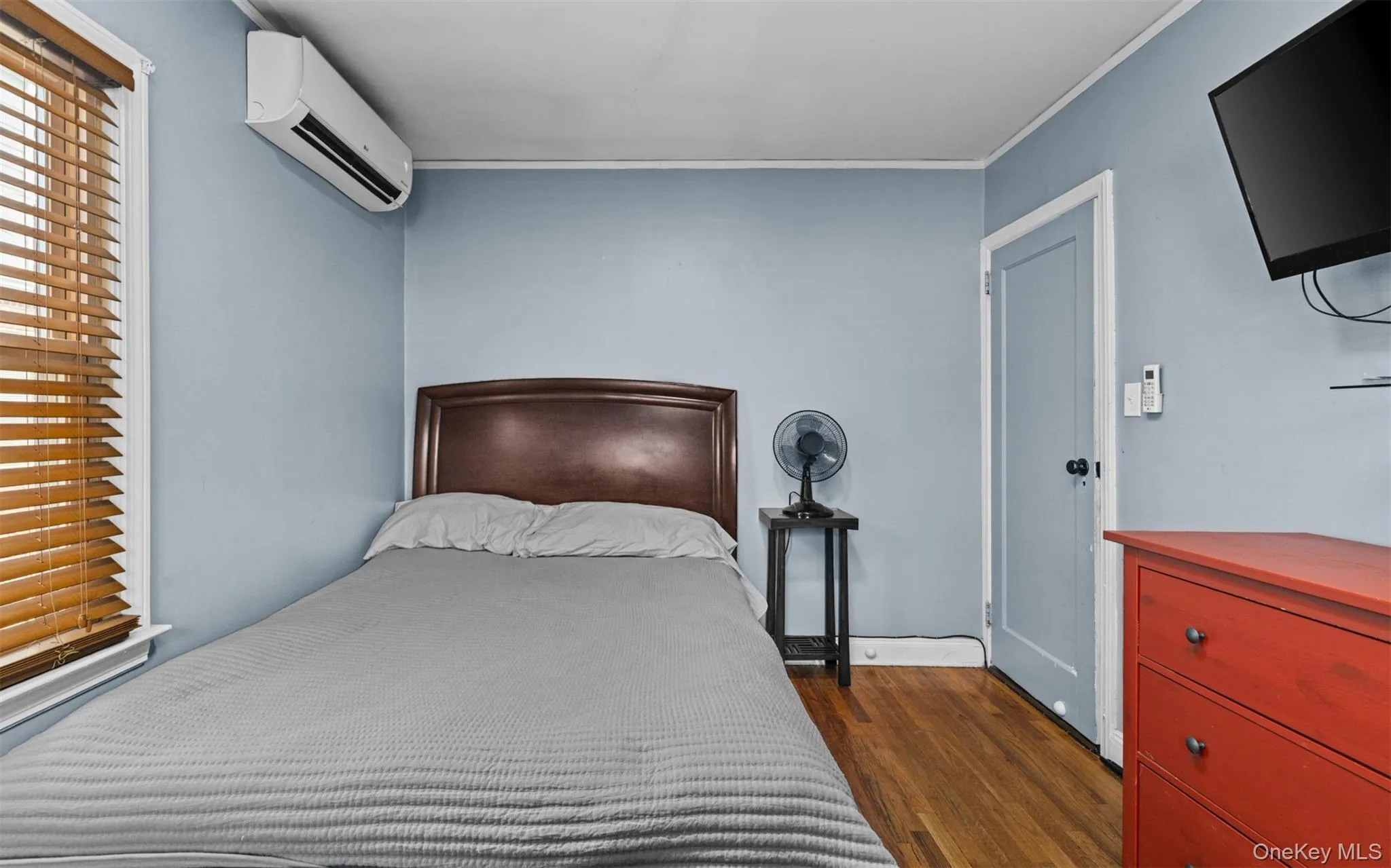 Bedroom with dark wood-style floors, an AC wall unit, and ornamental molding Bedroom with dark wood-style floors, an AC wall unit, and ornamental molding