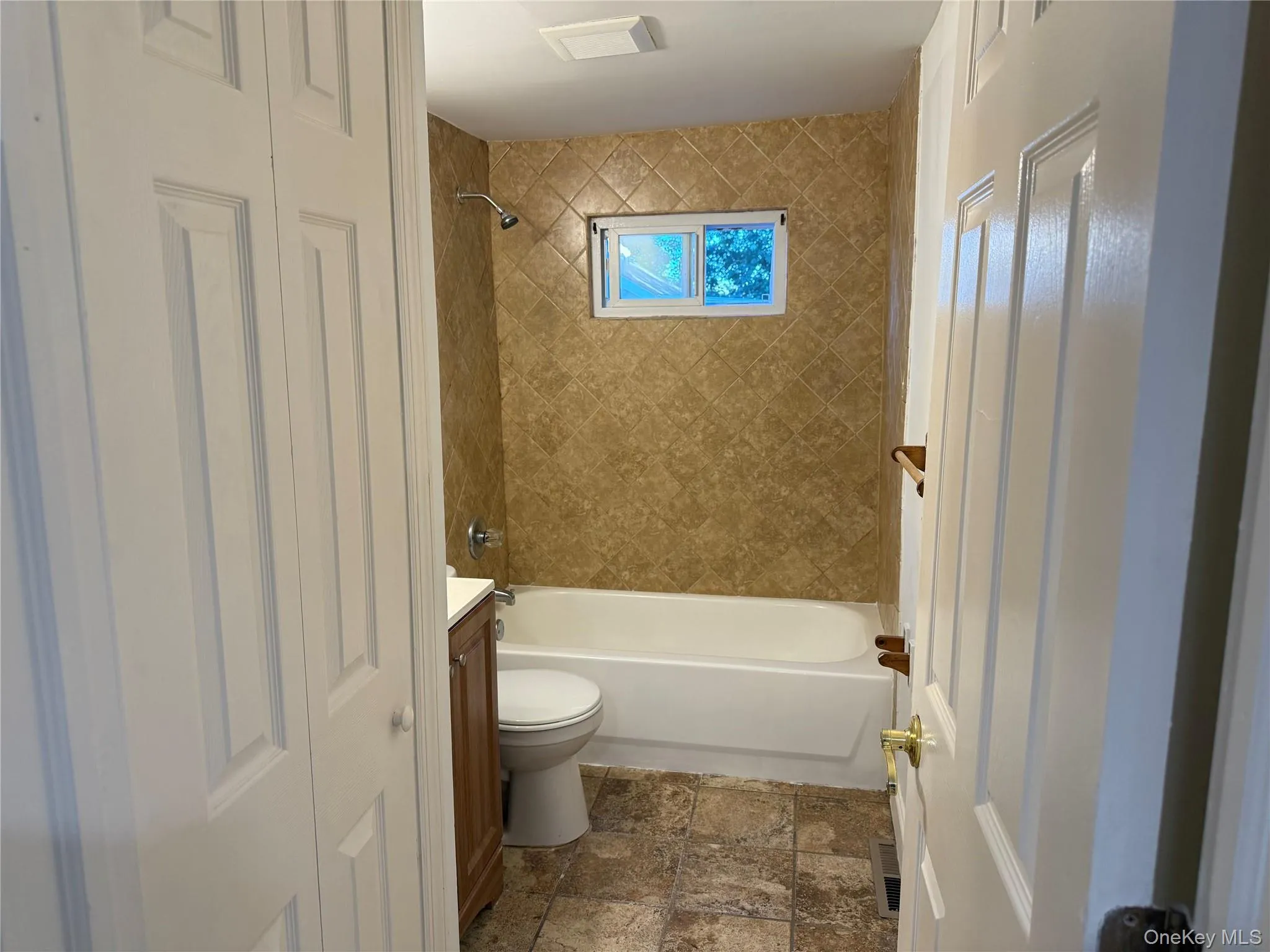 Bathroom with vanity, bathtub / shower combination, and dark stone finish floors Bathroom with vanity, bathtub / shower combination, and dark stone finish floors