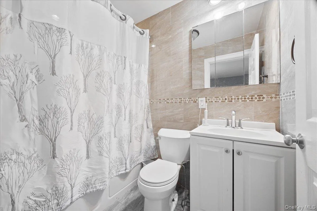 Full bath with tile walls, shower / bath combination with curtain, and vanity Full bath with tile walls, shower / bath combination with curtain, and vanity