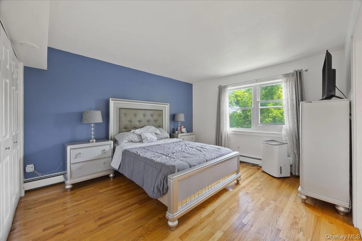 Bedroom featuring a closet, light wood finished floors, and baseboard heating Bedroom featuring a closet, light wood finished floors, and baseboard heating