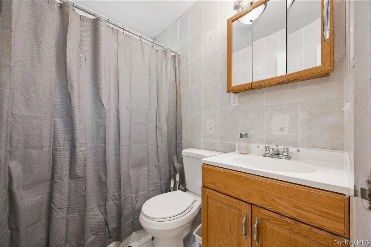 Full bathroom with tile walls, vanity, and decorative backsplash Full bathroom with tile walls, vanity, and decorative backsplash