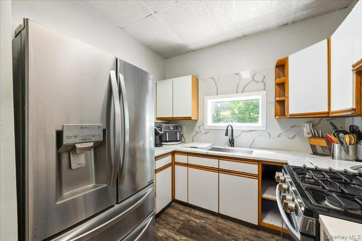 Kitchen featuring open shelves, appliances with stainless steel finishes, white cabinetry, and a paneled ceiling Kitchen featuring open shelves, appliances with stainless steel finishes, white cabinetry, and a paneled ceiling