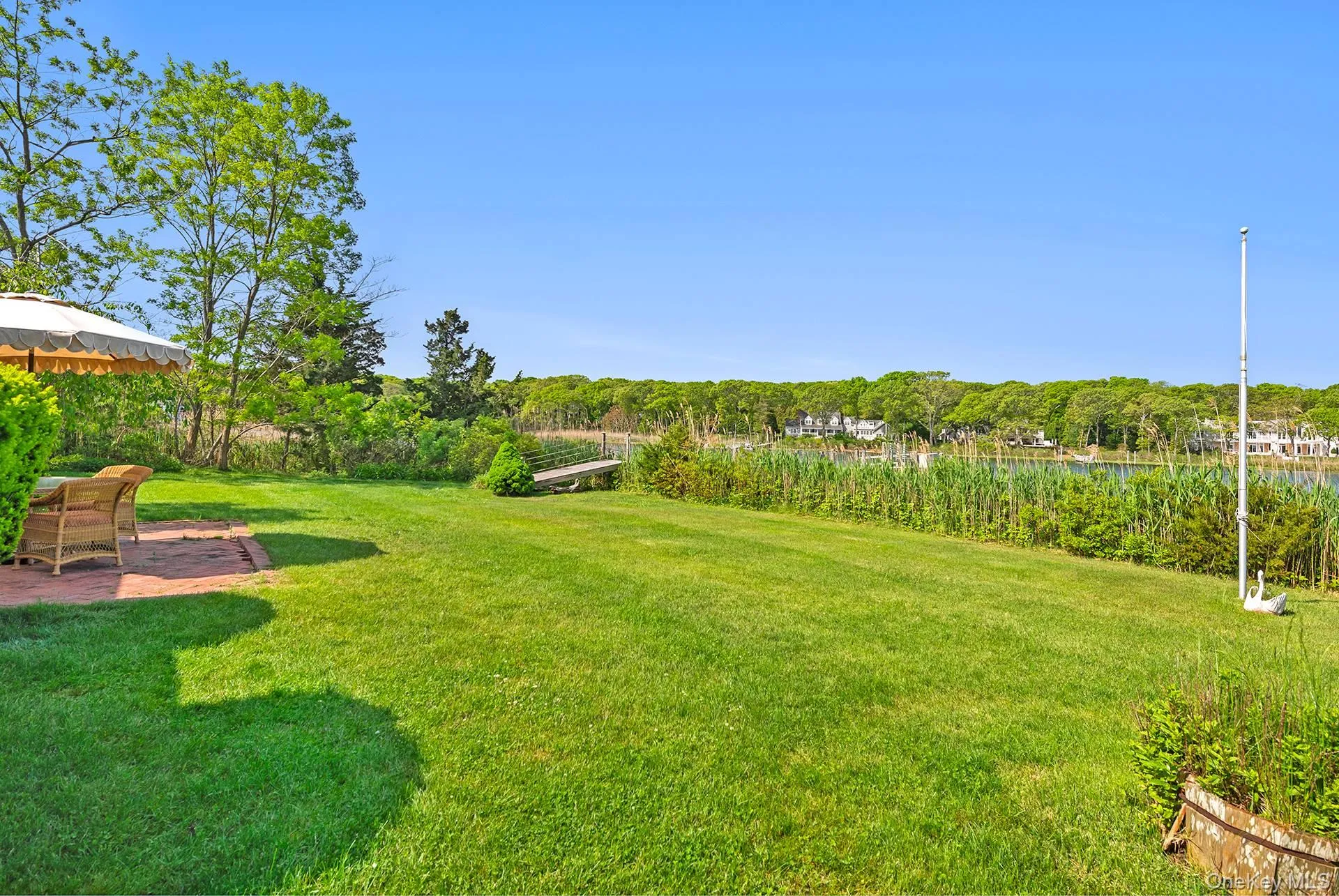 View of green lawn featuring a water view and a wooded view View of green lawn featuring a water view and a wooded view