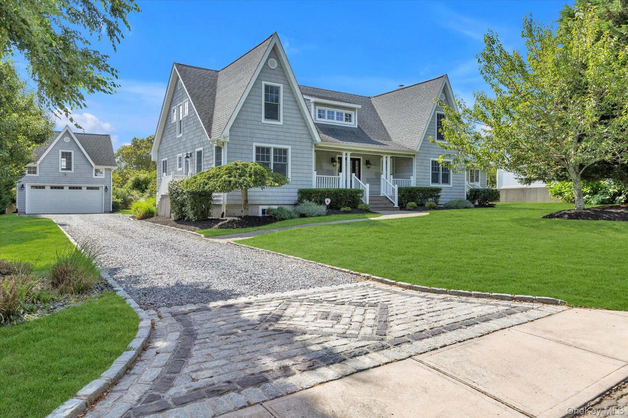 View of front of home featuring a front yard, covered porch, a garage, an outbuilding, and decorative driveway View of front of home featuring a front yard, covered porch, a garage, an outbuilding, and decorative driveway