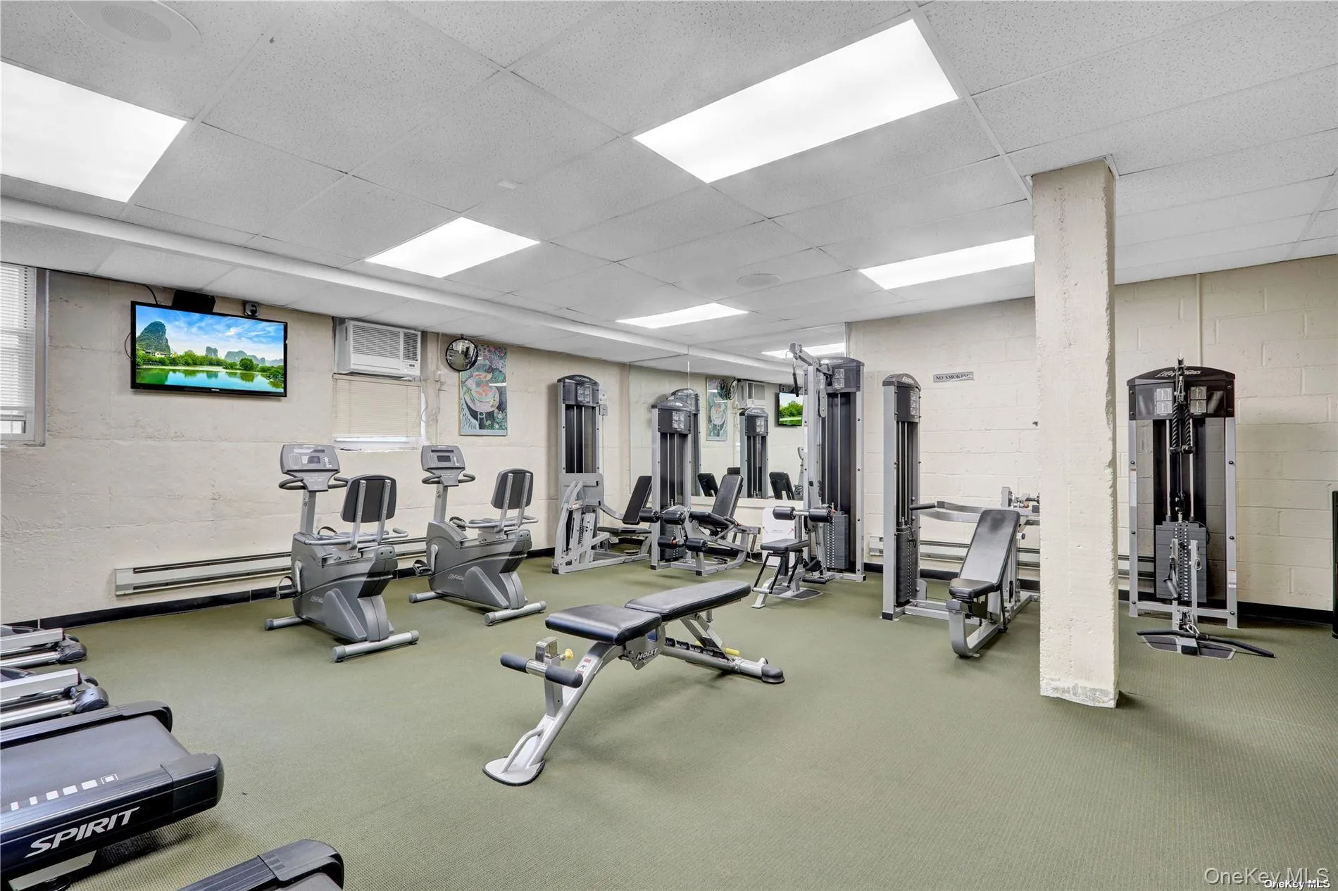Gym with concrete block wall, a drop ceiling, and baseboard heating Gym with concrete block wall, a drop ceiling, and baseboard heating