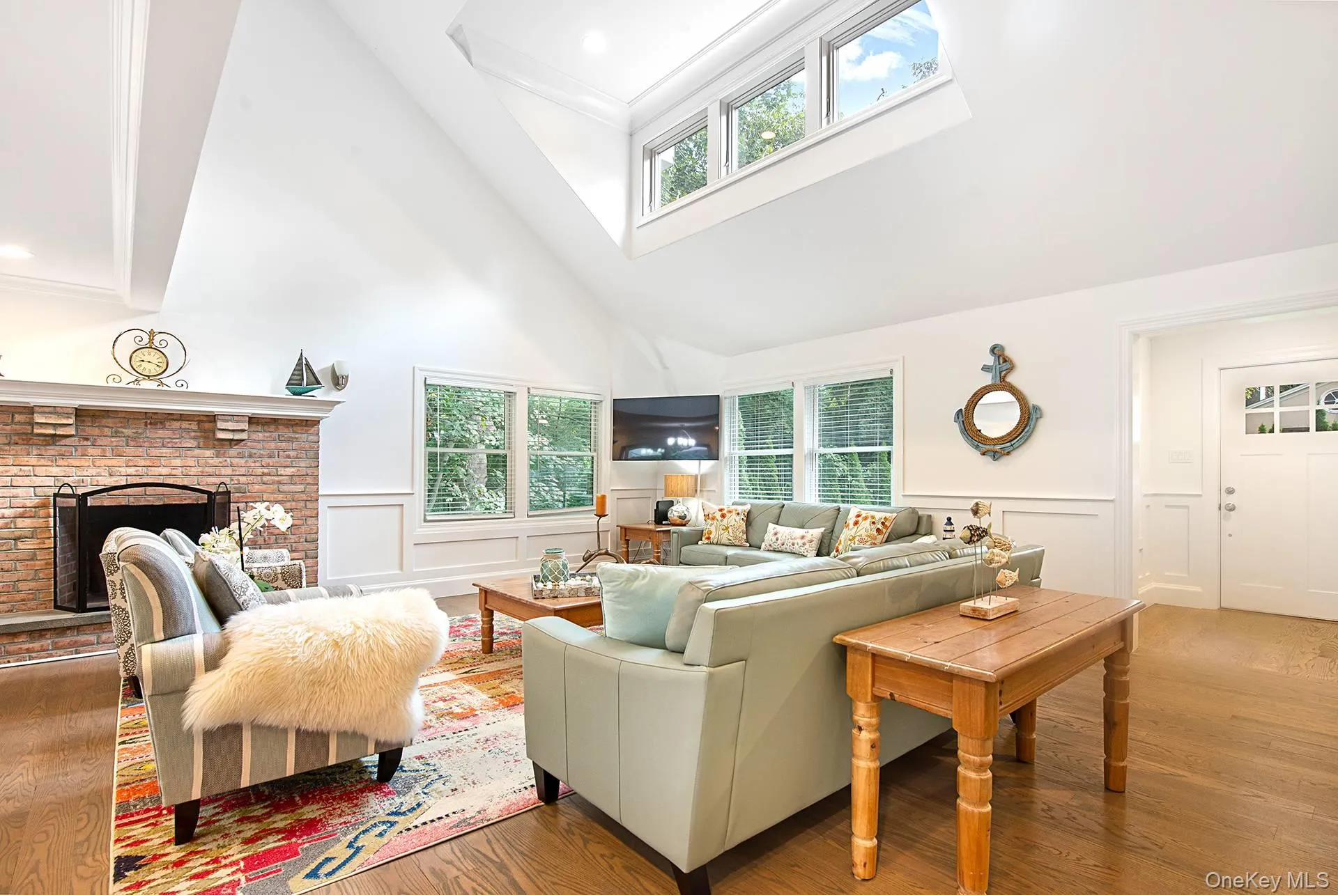 Living area with wood finished floors, a fireplace, a towering ceiling, healthy amount of natural light, and ornamental molding Living area with wood finished floors, a fireplace, a towering ceiling, healthy amount of natural light, and ornamental molding