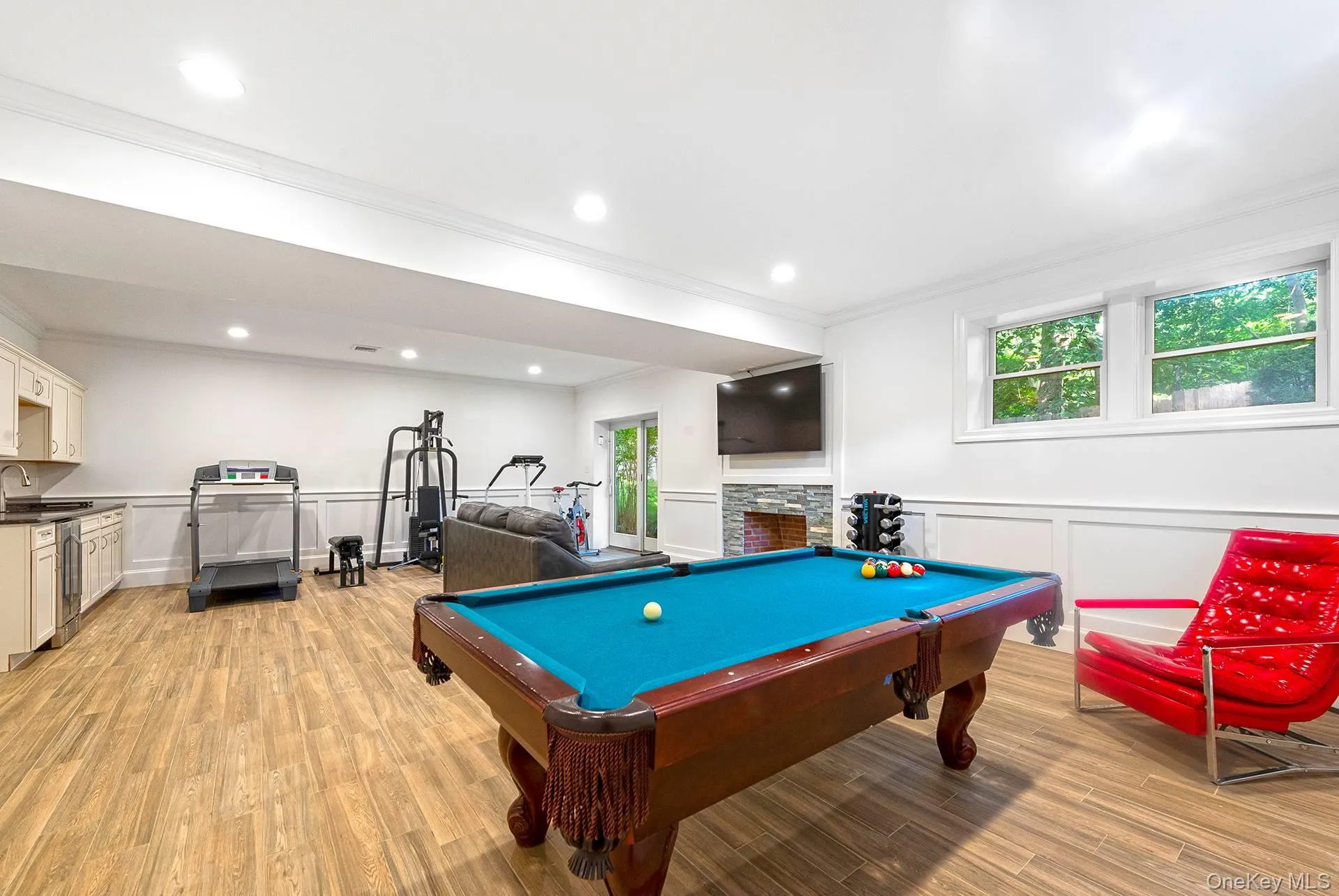 Recreation room featuring wainscoting, billiards table, a decorative wall, ornamental molding, and light wood-type flooring Recreation room featuring wainscoting, billiards table, a decorative wall, ornamental molding, and light wood-type flooring