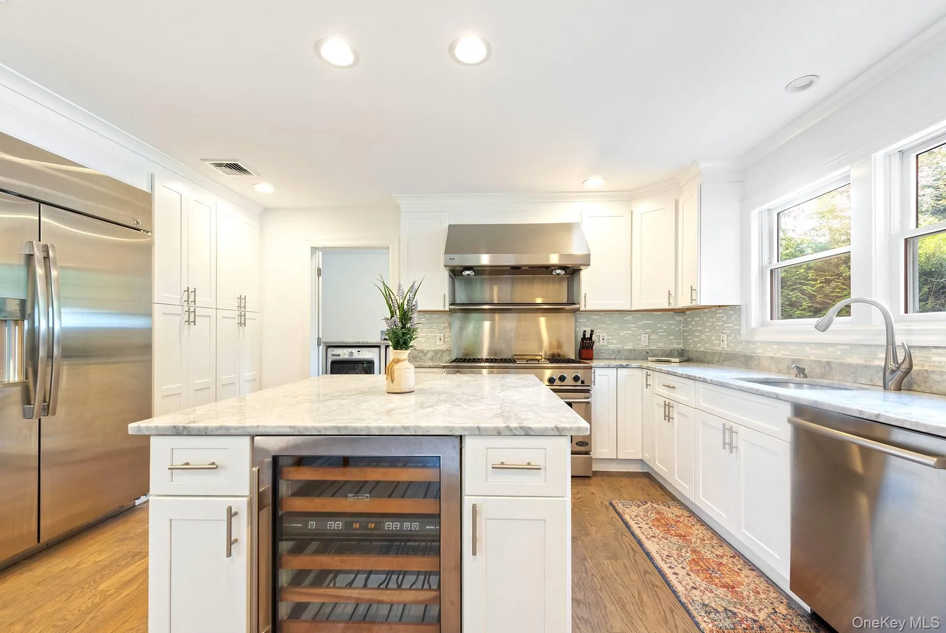 Kitchen featuring white cabinetry, appliances with stainless steel finishes, wine cooler, light stone counters, and recessed lighting Kitchen featuring white cabinetry, appliances with stainless steel finishes, wine cooler, light stone counters, and recessed lighting