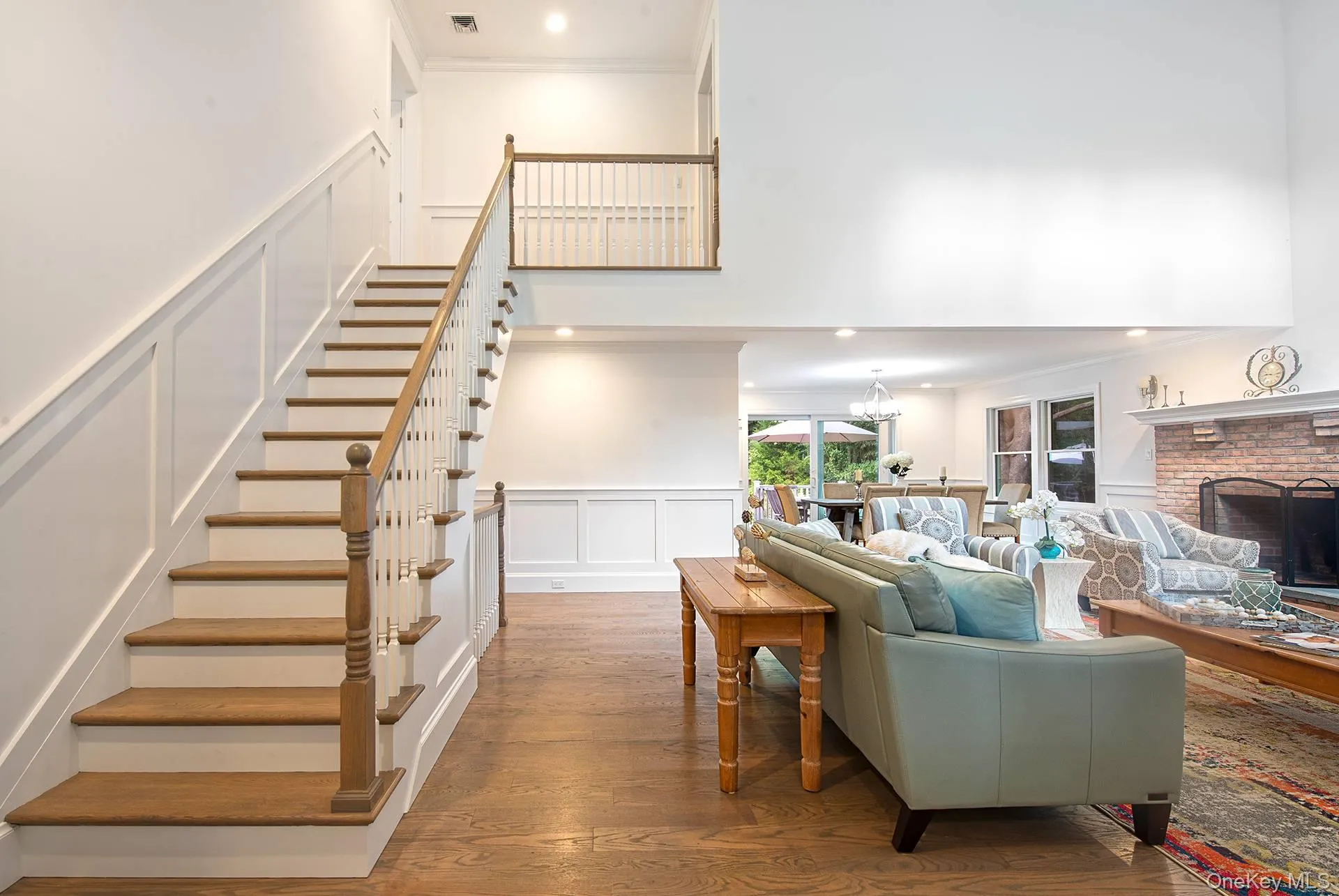 Living room with a decorative wall, wainscoting, wood finished floors, recessed lighting, and a brick fireplace Living room with a decorative wall, wainscoting, wood finished floors, recessed lighting, and a brick fireplace