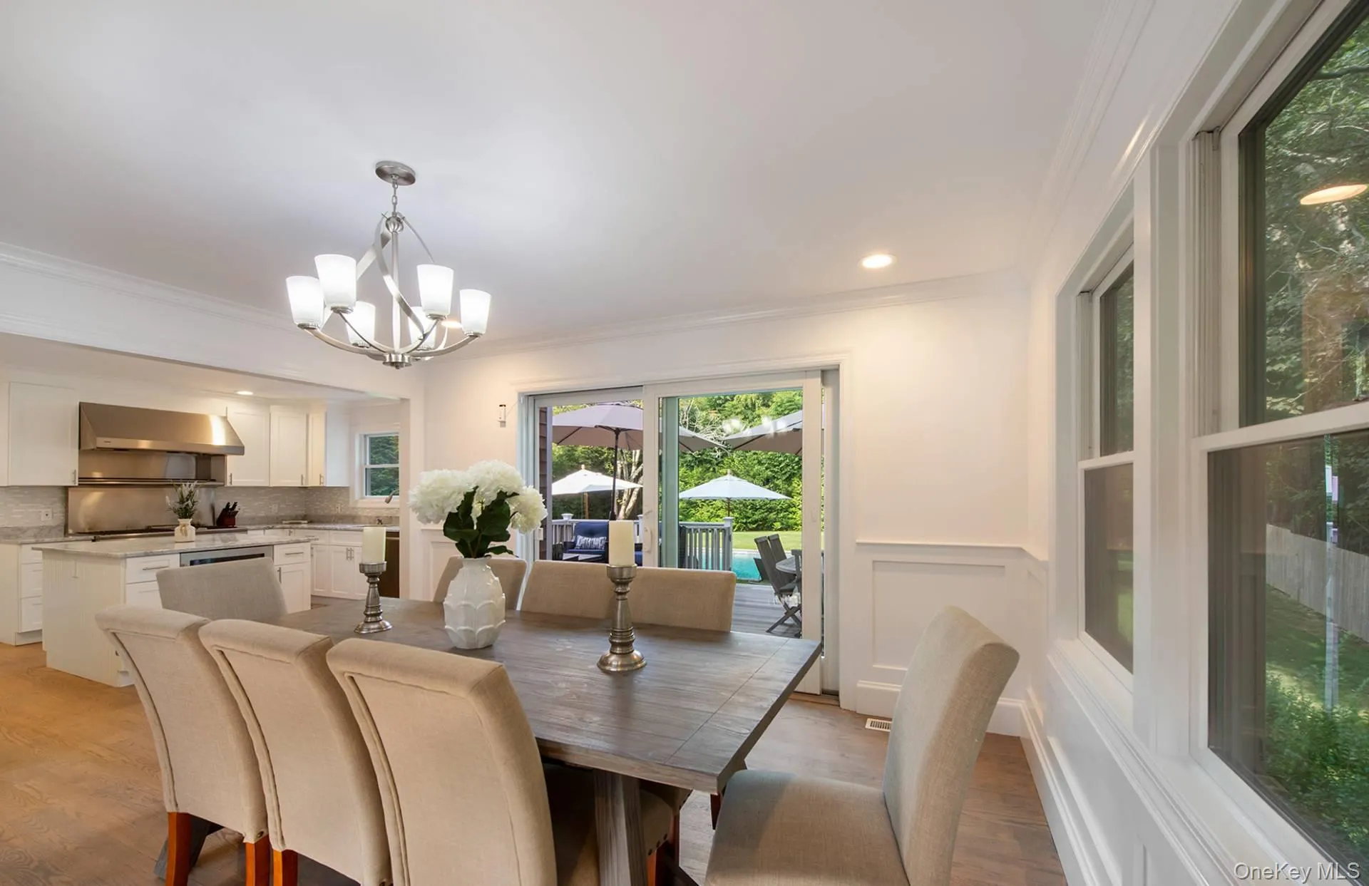 Dining area featuring ornamental molding, a chandelier, light wood-style flooring, recessed lighting, and a wainscoted wall Dining area featuring ornamental molding, a chandelier, light wood-style flooring, recessed lighting, and a wainscoted wall