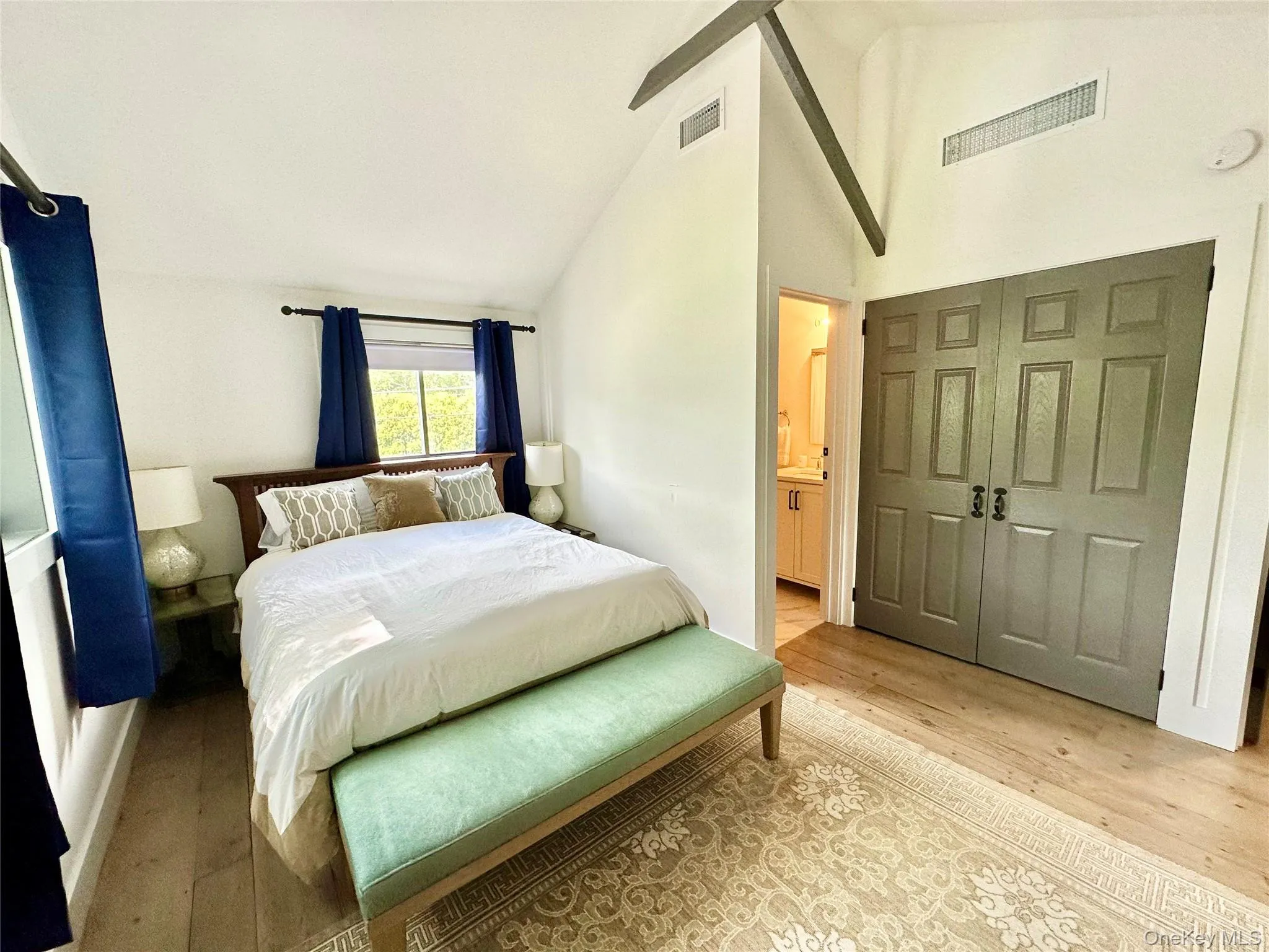 Bedroom featuring light wood finished floors, a closet, high vaulted ceiling, and ensuite bath Bedroom featuring light wood finished floors, a closet, high vaulted ceiling, and ensuite bath