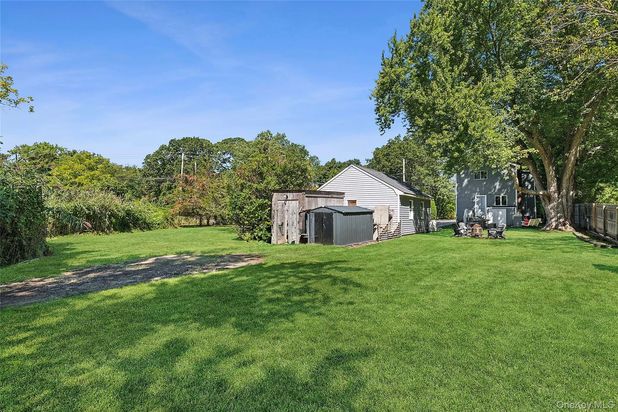 View of green lawn featuring a storage shed and view of wooded area View of green lawn featuring a storage shed and view of wooded area