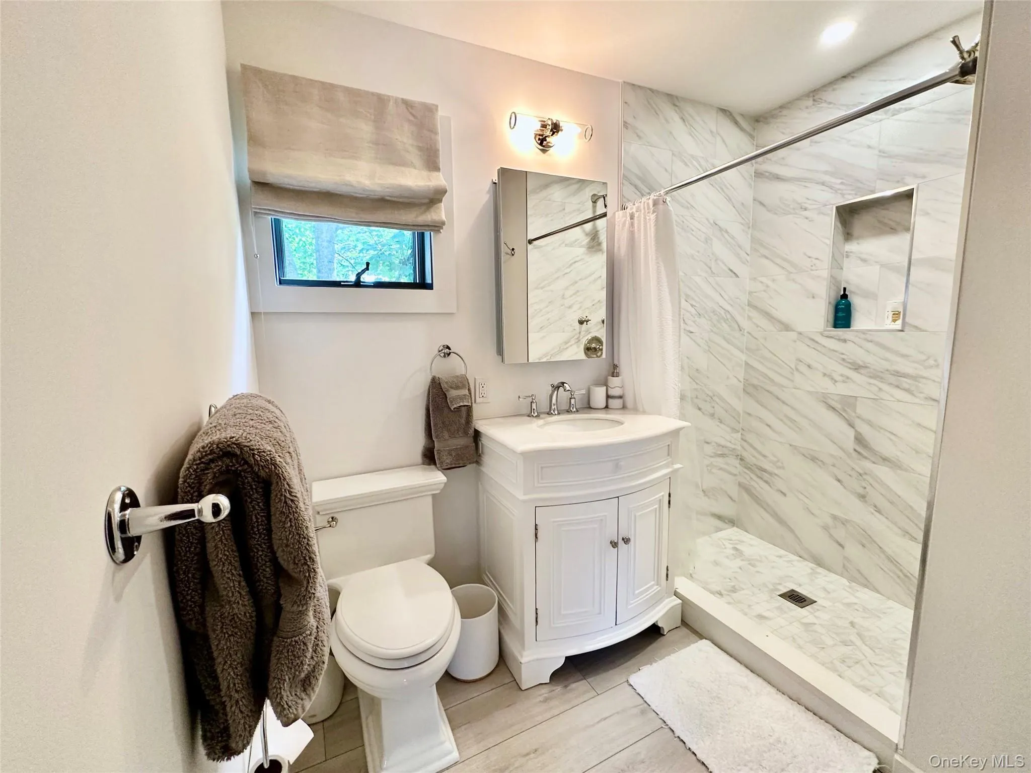 Full bathroom featuring a stall shower, vanity, and wood finish floors Full bathroom featuring a stall shower, vanity, and wood finish floors