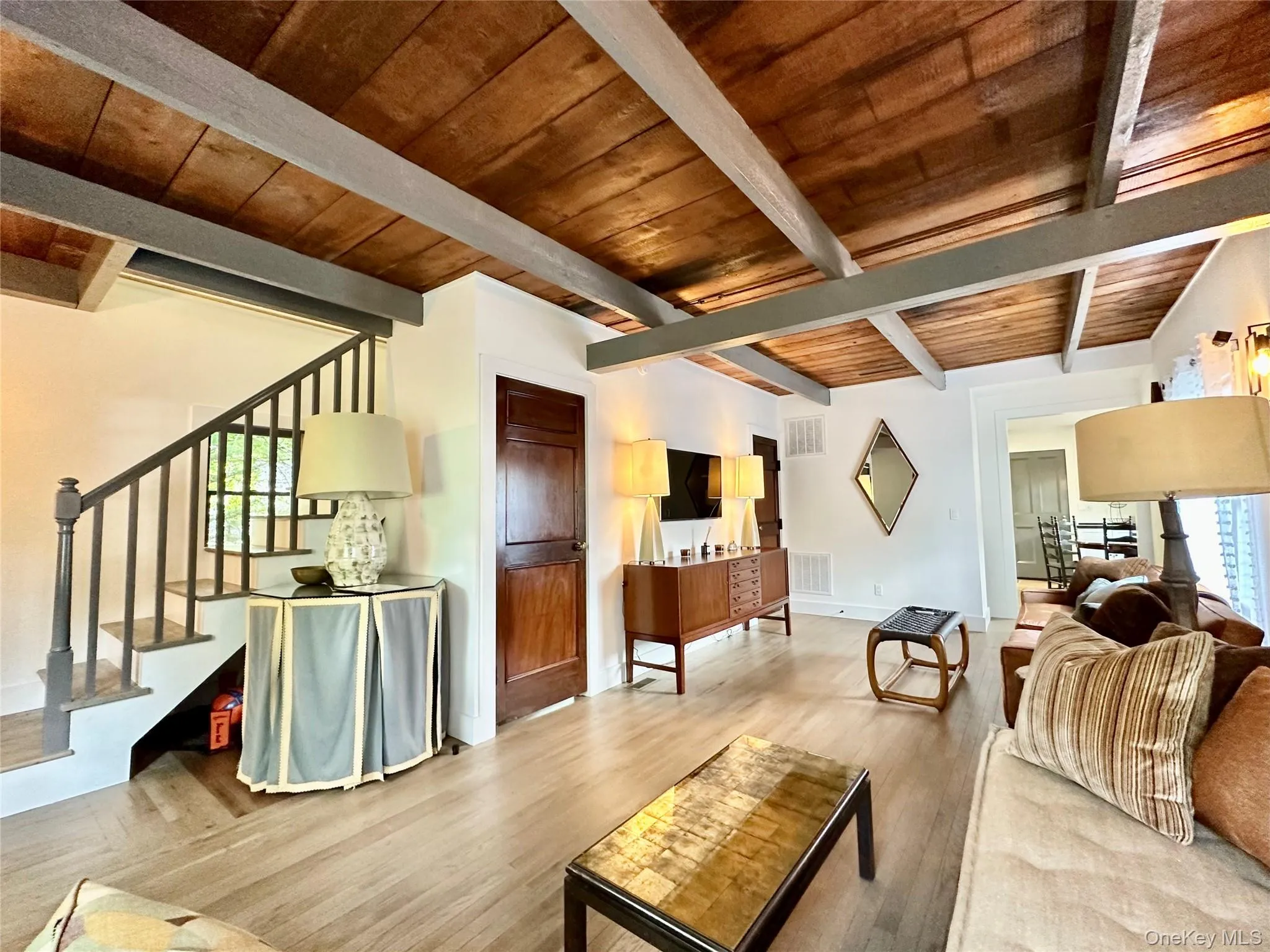 Living room featuring stairway, wood finished floors, and a wooden ceiling with exposed beams Living room featuring stairway, wood finished floors, and a wooden ceiling with exposed beams