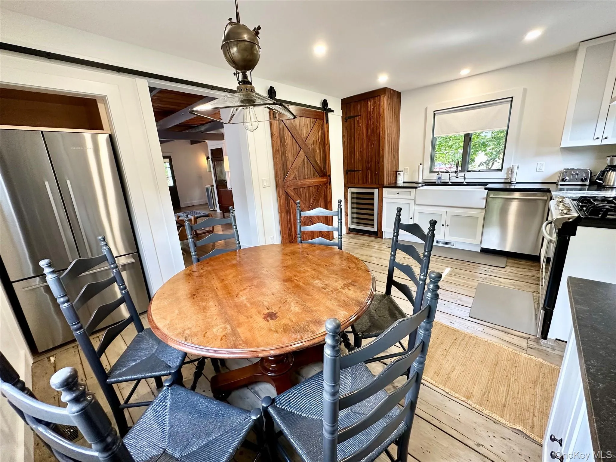 Dining space featuring a barn door, light wood-style floors, wine cooler, and recessed lighting Dining space featuring a barn door, light wood-style floors, wine cooler, and recessed lighting