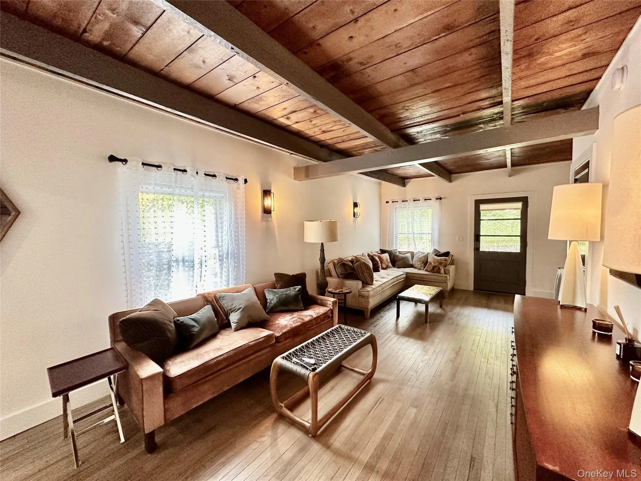 Living area featuring healthy amount of natural light, hardwood / wood-style floors, and a wooden ceiling with exposed beams Living area featuring healthy amount of natural light, hardwood / wood-style floors, and a wooden ceiling with exposed beams