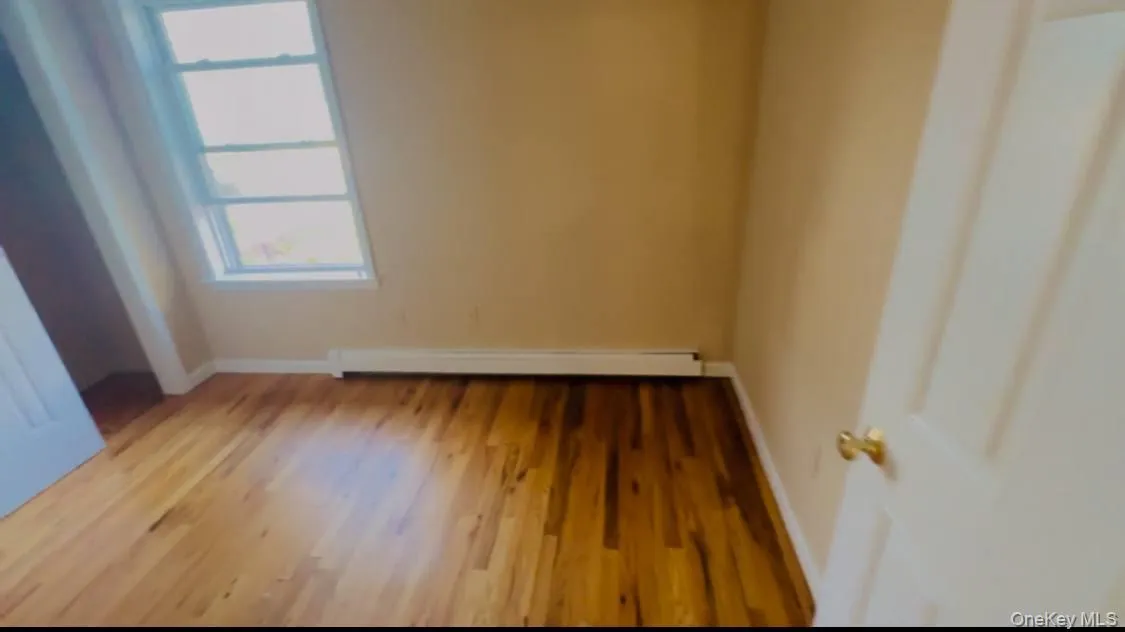 Spare room featuring wood finished floors and a baseboard heating unit Spare room featuring wood finished floors and a baseboard heating unit