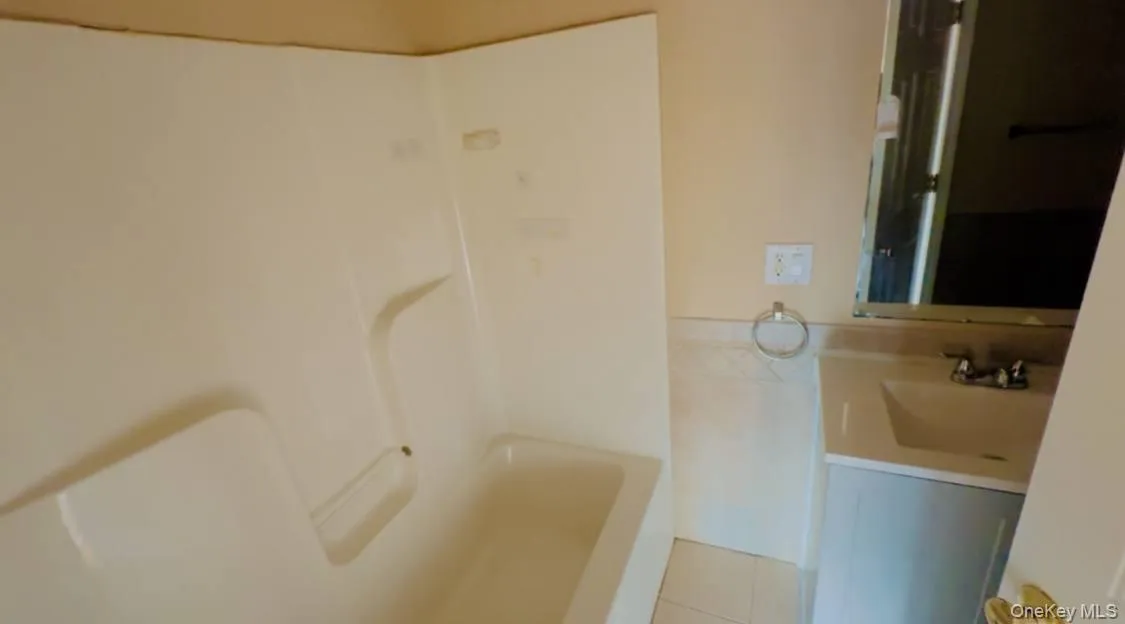 Full bath featuring vanity and light tile patterned floors Full bath featuring vanity and light tile patterned floors