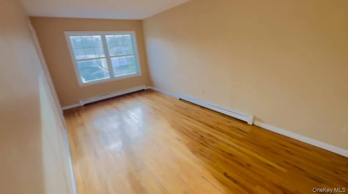Empty room featuring light wood-type flooring and a baseboard radiator Empty room featuring light wood-type flooring and a baseboard radiator