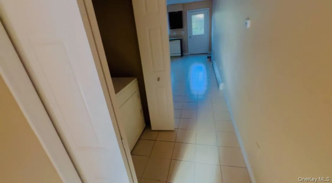 Hallway with light tile patterned flooring and washer / dryer Hallway with light tile patterned flooring and washer / dryer