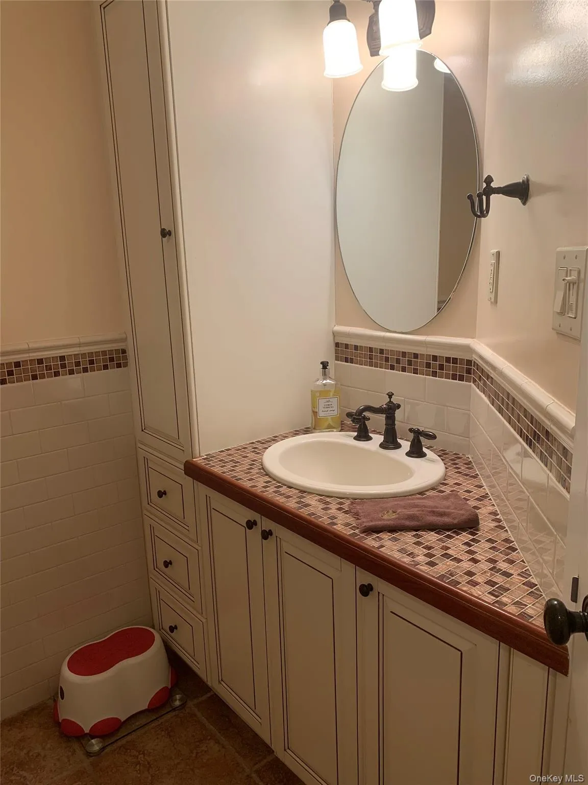 Bathroom with vanity, tile walls, and dark tile patterned floors Bathroom with vanity, tile walls, and dark tile patterned floors
