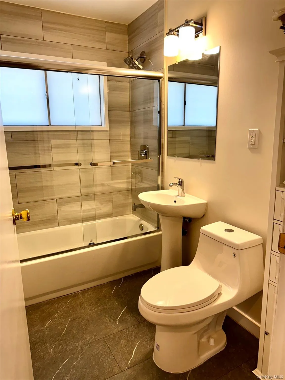 Full bathroom featuring shower / bath combination with glass door and dark tile patterned floors Full bathroom featuring shower / bath combination with glass door and dark tile patterned floors