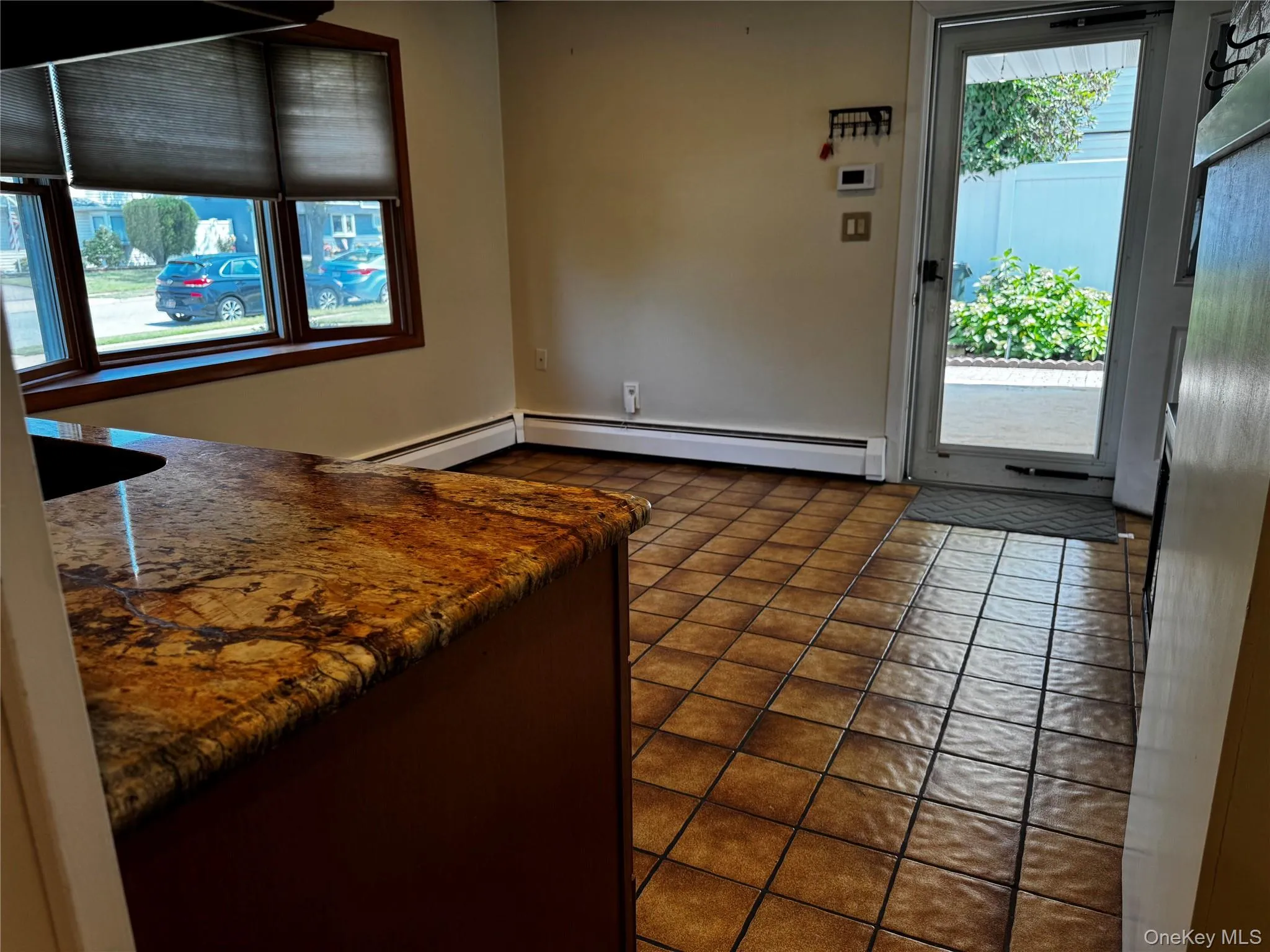 Kitchen with a baseboard heating unit, dark stone countertops, and dark tile patterned floors Kitchen with a baseboard heating unit, dark stone countertops, and dark tile patterned floors