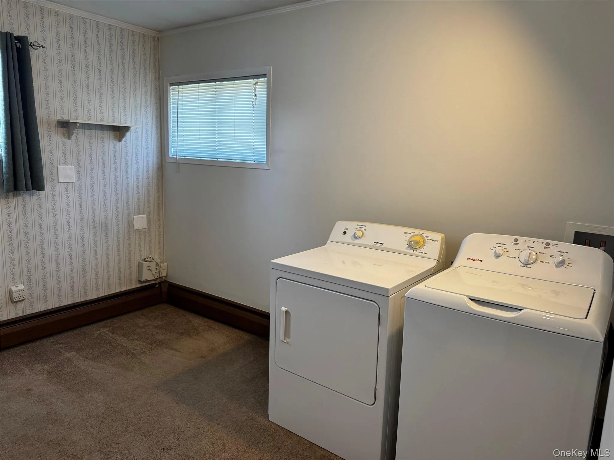 Washroom featuring ornamental molding, dark carpet, and washing machine and clothes dryer Washroom featuring ornamental molding, dark carpet, and washing machine and clothes dryer