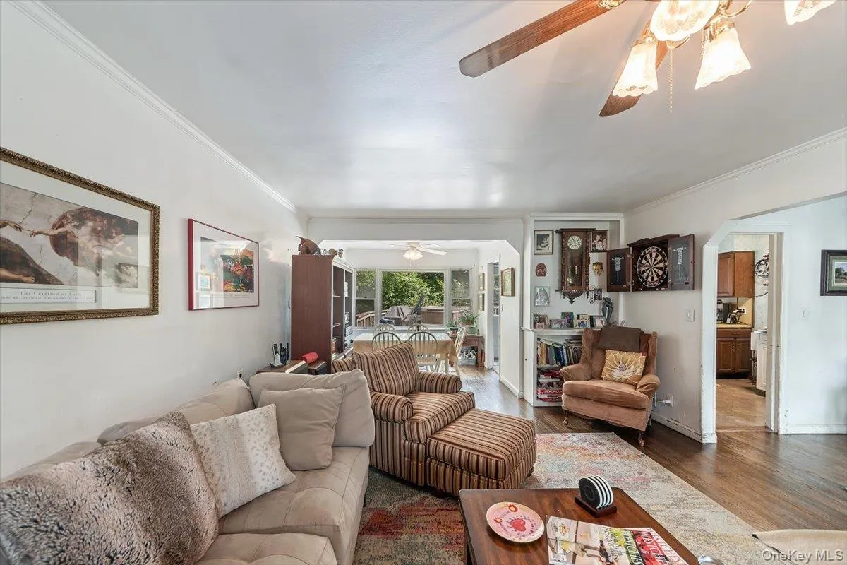 Living area featuring wood finished floors, crown molding, and ceiling fan Living area featuring wood finished floors, crown molding, and ceiling fan