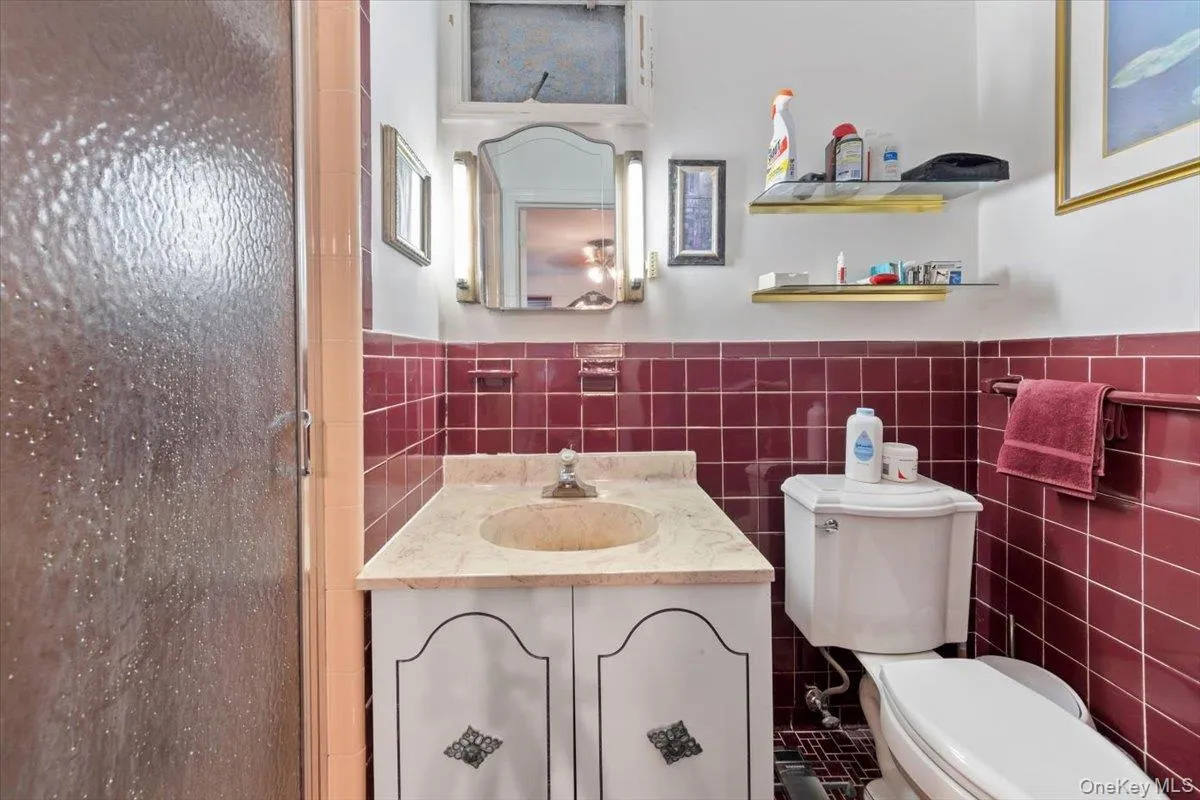Bathroom with tile walls, vanity, a shower stall, and wainscoting Bathroom with tile walls, vanity, a shower stall, and wainscoting