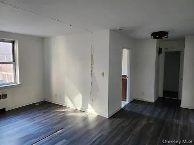 Unfurnished room featuring dark wood-style flooring and baseboards Unfurnished room featuring dark wood-style flooring and baseboards