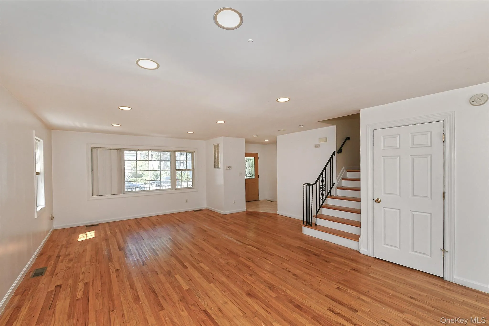Unfurnished living room with recessed lighting, light wood-type flooring, and stairs Unfurnished living room with recessed lighting, light wood-type flooring, and stairs
